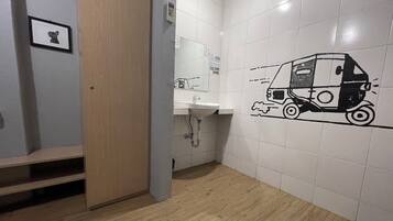 A restroom with a sink, a toilet, and a wall with a black and white drawing of a delivery truck.
