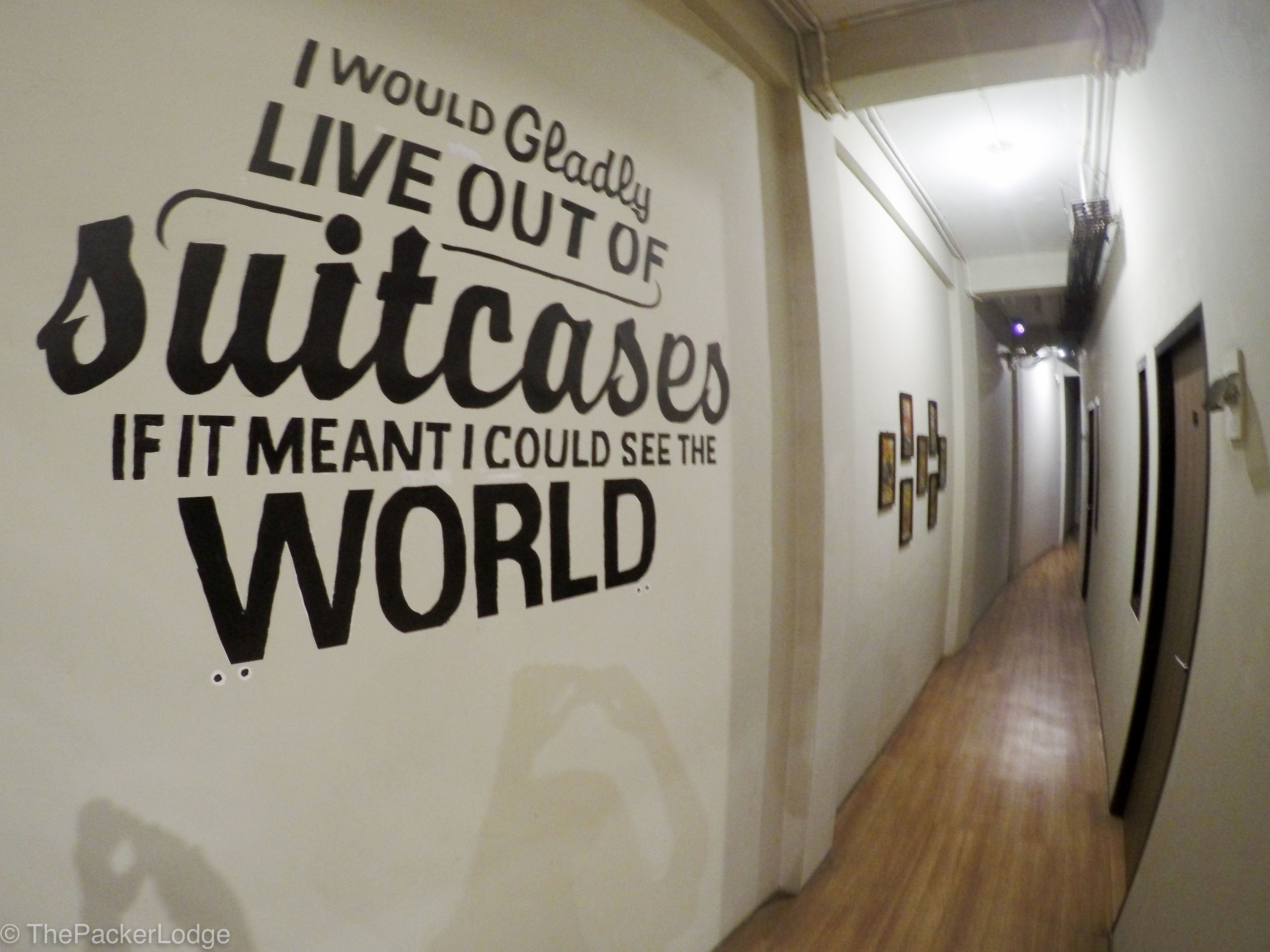A hallway with a motivational quote on the wall and wooden flooring.