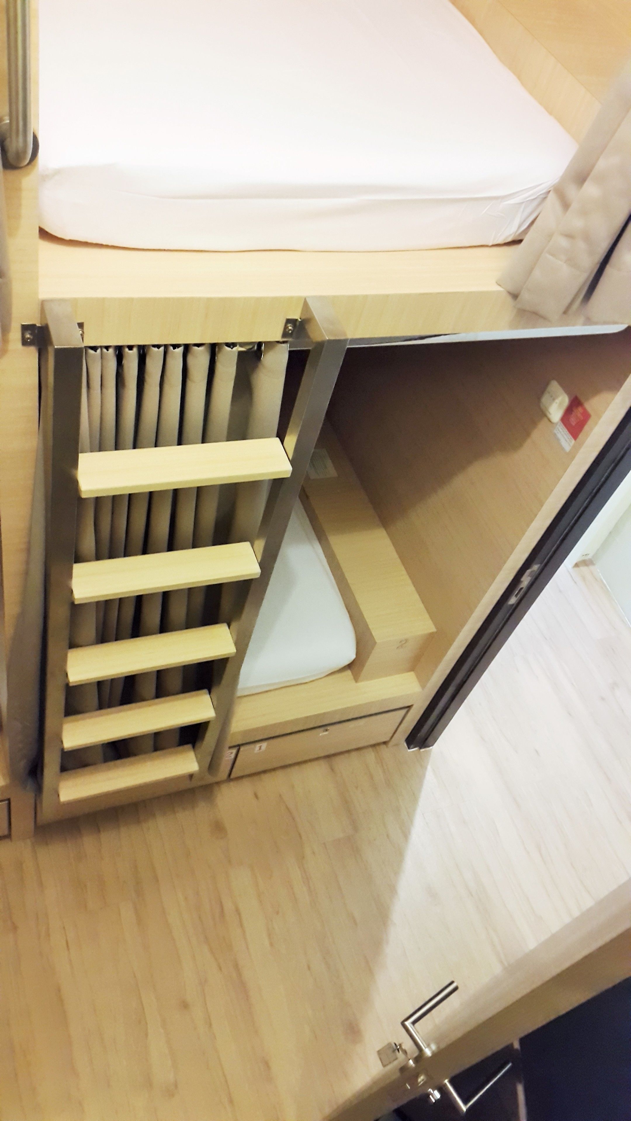 A compact, wooden-framed bed with a built-in storage compartment underneath.