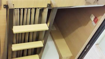 A compact, wooden-framed bed with a built-in storage compartment underneath.