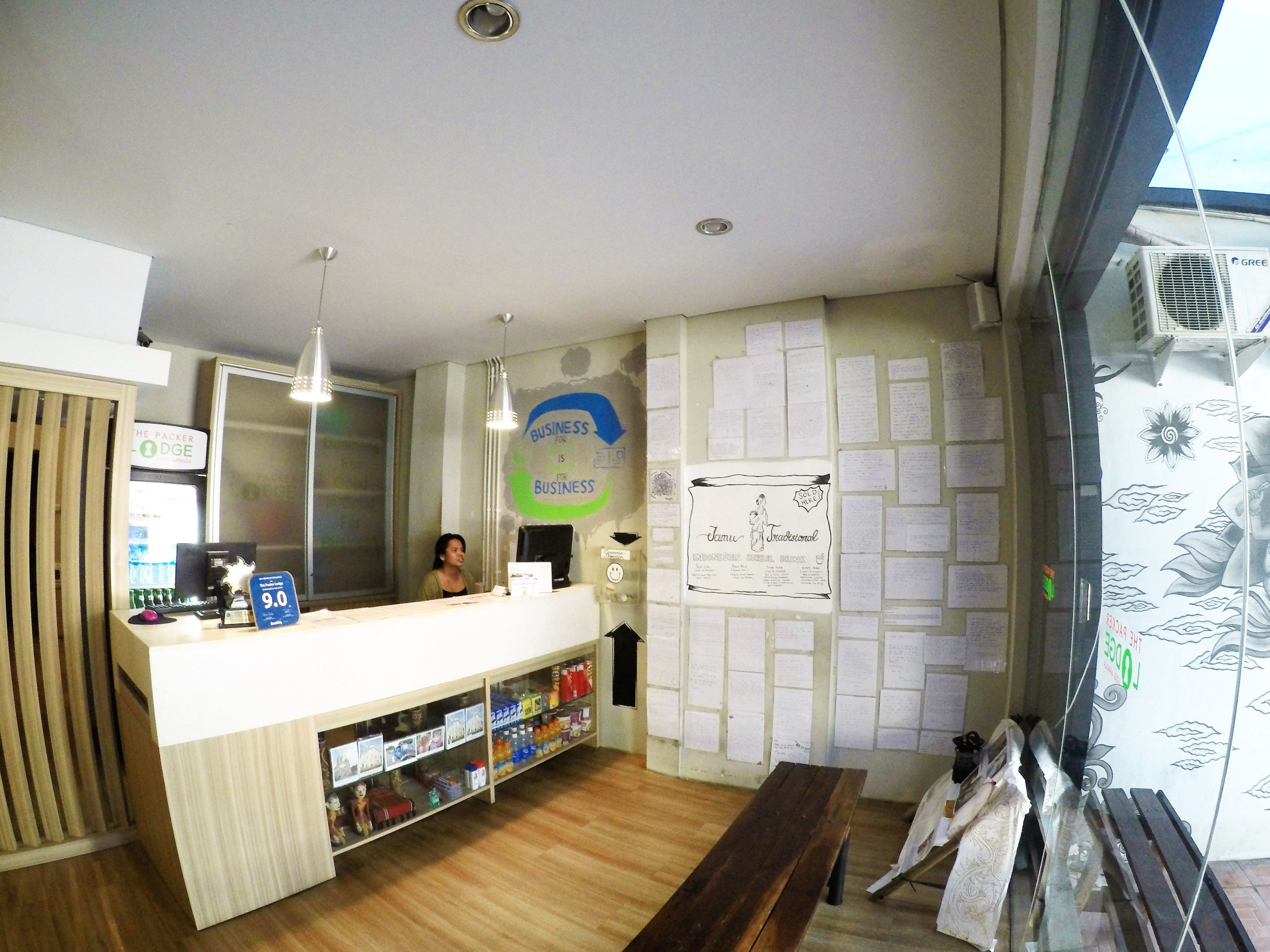 A reception desk with a counter, a computer, and a wall with notes and a drawing.