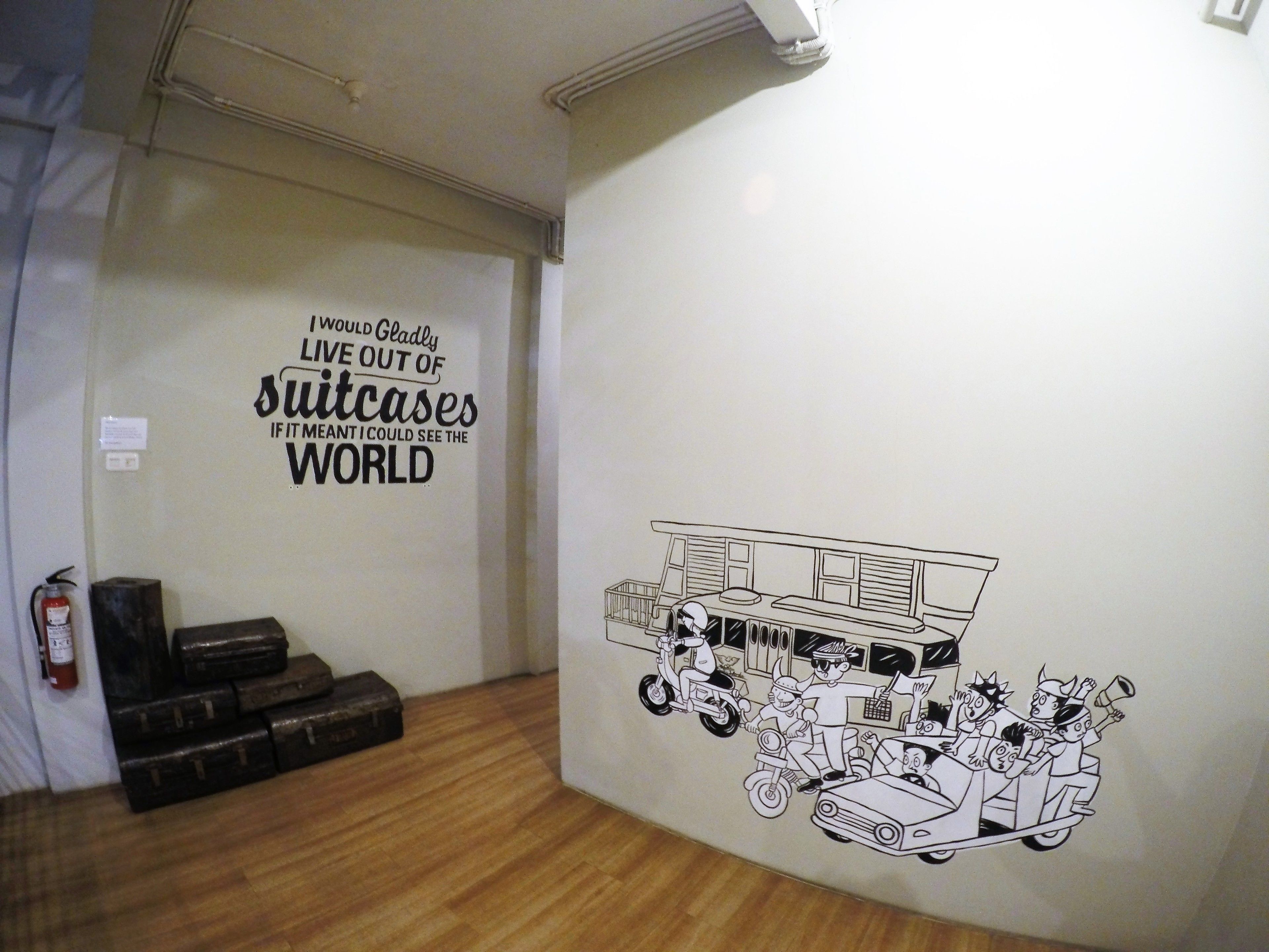 Habitació amb un mural que inclou una cita i un dibuix d'un vehicle amb persones.