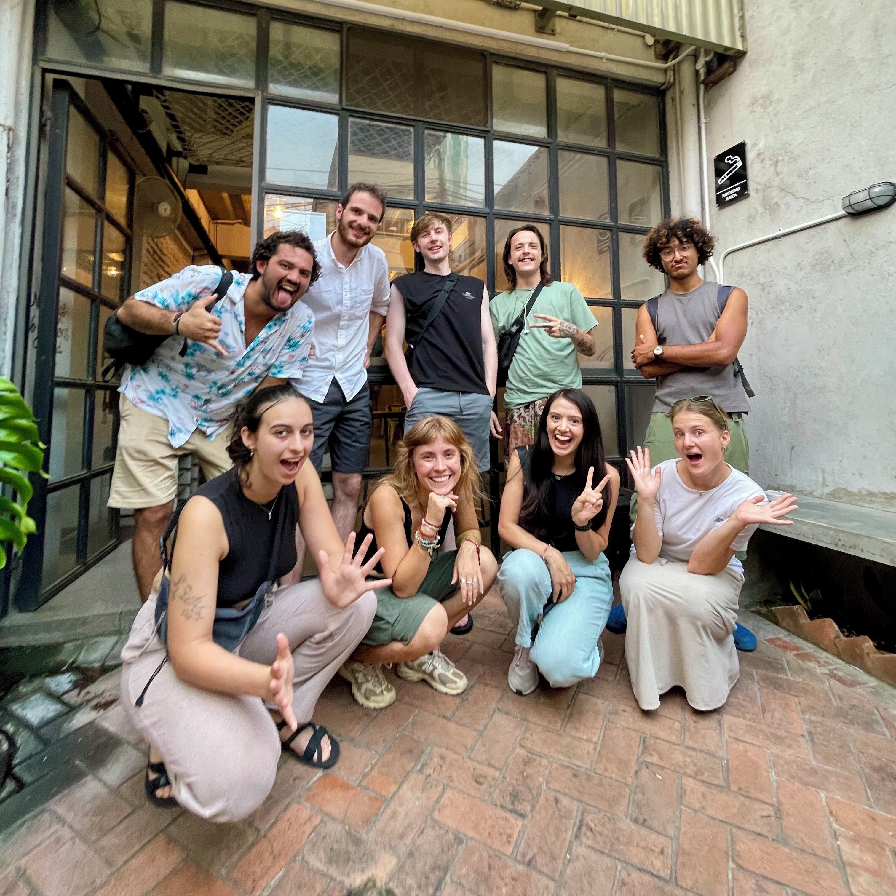 A group of people posing in front of a building with large windows and a brick patio.