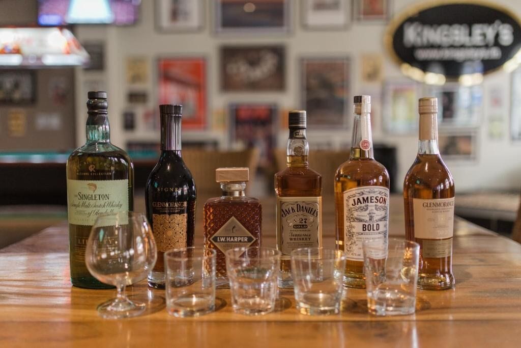 A bar setting with various bottles of whiskey and glasses.