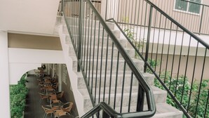 A staircase with black railings leading to a lower level with outdoor seating. - Kingsley's Hotel and Gastro Pub (Mabalacat City)