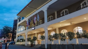 A hotel with a two-story facade, multiple balconies, and flags. - Kingsley's Hotel and Gastro Pub (Mabalacat City)