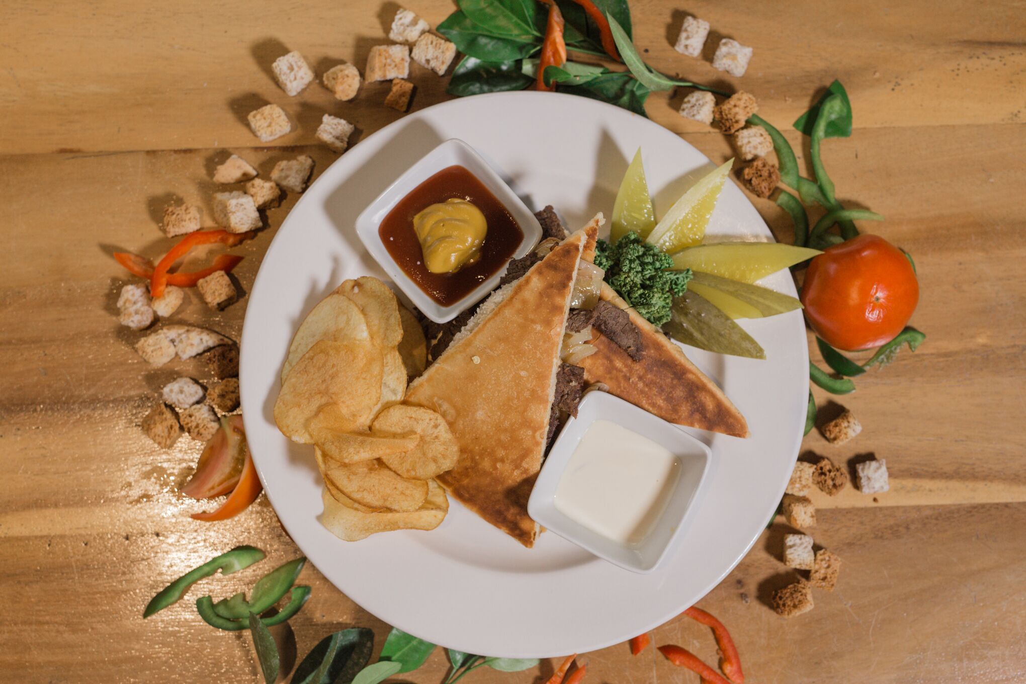 Un plato con un sándwich, papas fritas y un pequeño recipiente de salsa.