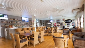 A bar area with wicker furniture, a counter with bottles, and a sign reading "Kingsley's". - Kingsley's Hotel and Gastro Pub (Mabalacat City)