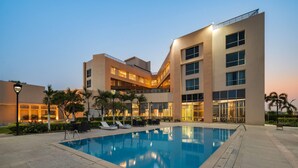 A hotel with a swimming pool, outdoor seating, and a modern architectural design.