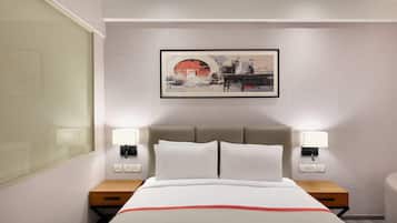 Una habitación de hotel con cama, lámparas de noche, una obra de arte en la pared y una mesita de noche.