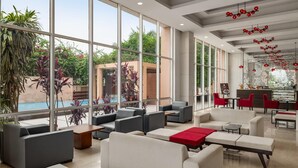 A spacious indoor area with large windows, seating arrangements, and a pool visible outside.