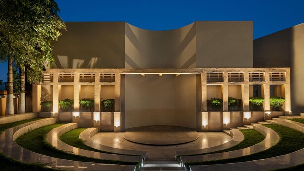A modern building with a central courtyard, surrounded by a circular pathway and steps leading to the entrance.