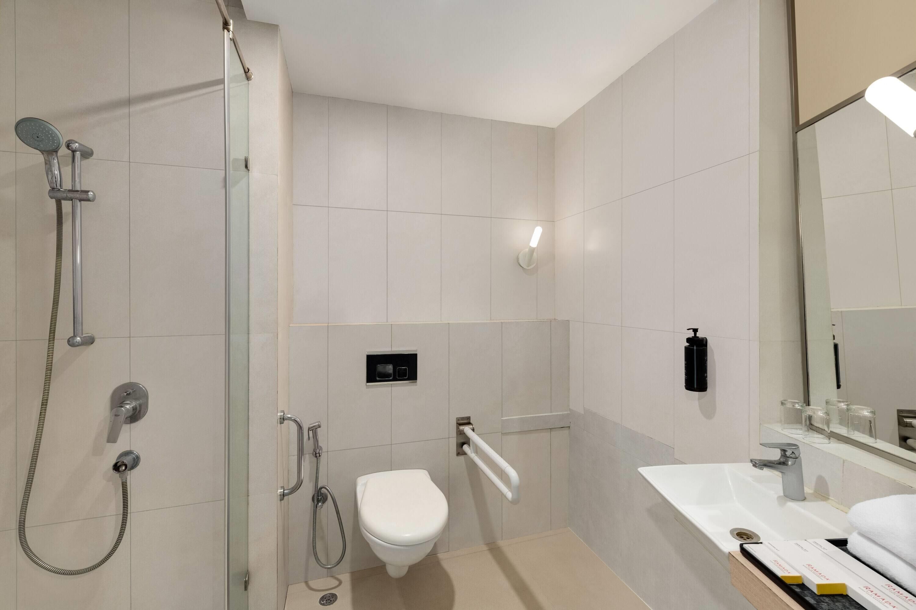 A modern bathroom with a glass shower enclosure, a toilet, a sink with a mirror, and a towel rack.