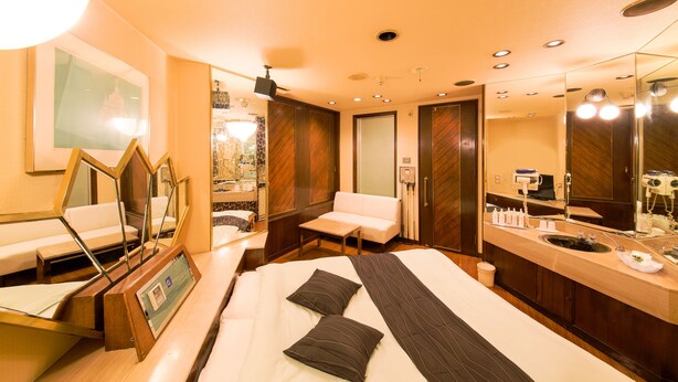 A hotel room with a bed, a sitting area, a vanity with a mirror, and a large window. - Hotel Public Jam (Osaka)