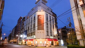 A hotel with a prominent sign, multiple floors, and a street view with other buildings and a clear sky. - Hotel Public Jam (Osaka)