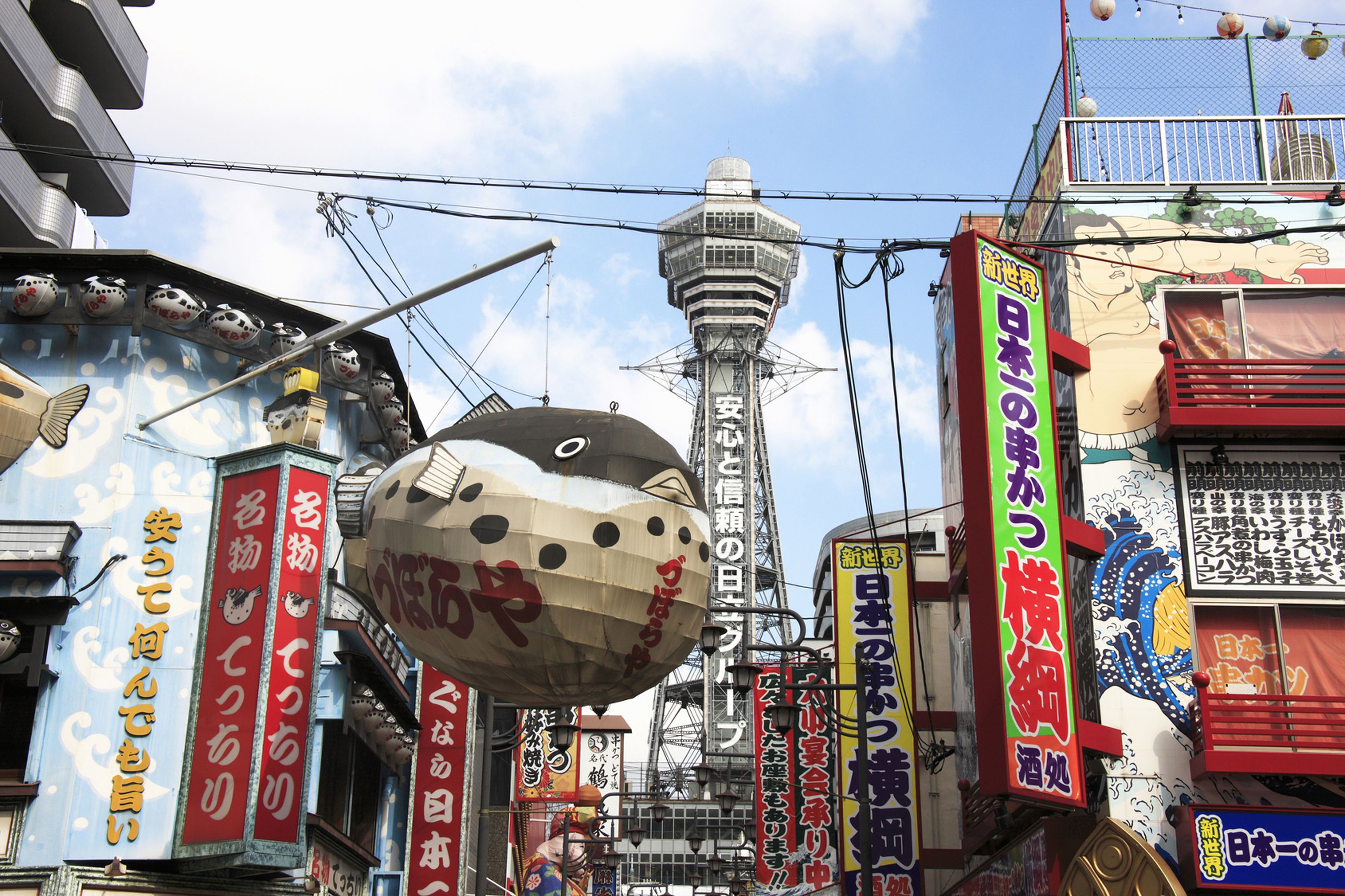 A busy urban street with various signs and a large spherical structure.