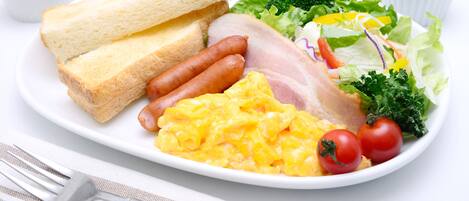 A breakfast plate with toast, sausages, scrambled eggs, bacon, tomatoes, lettuce, and a side salad.