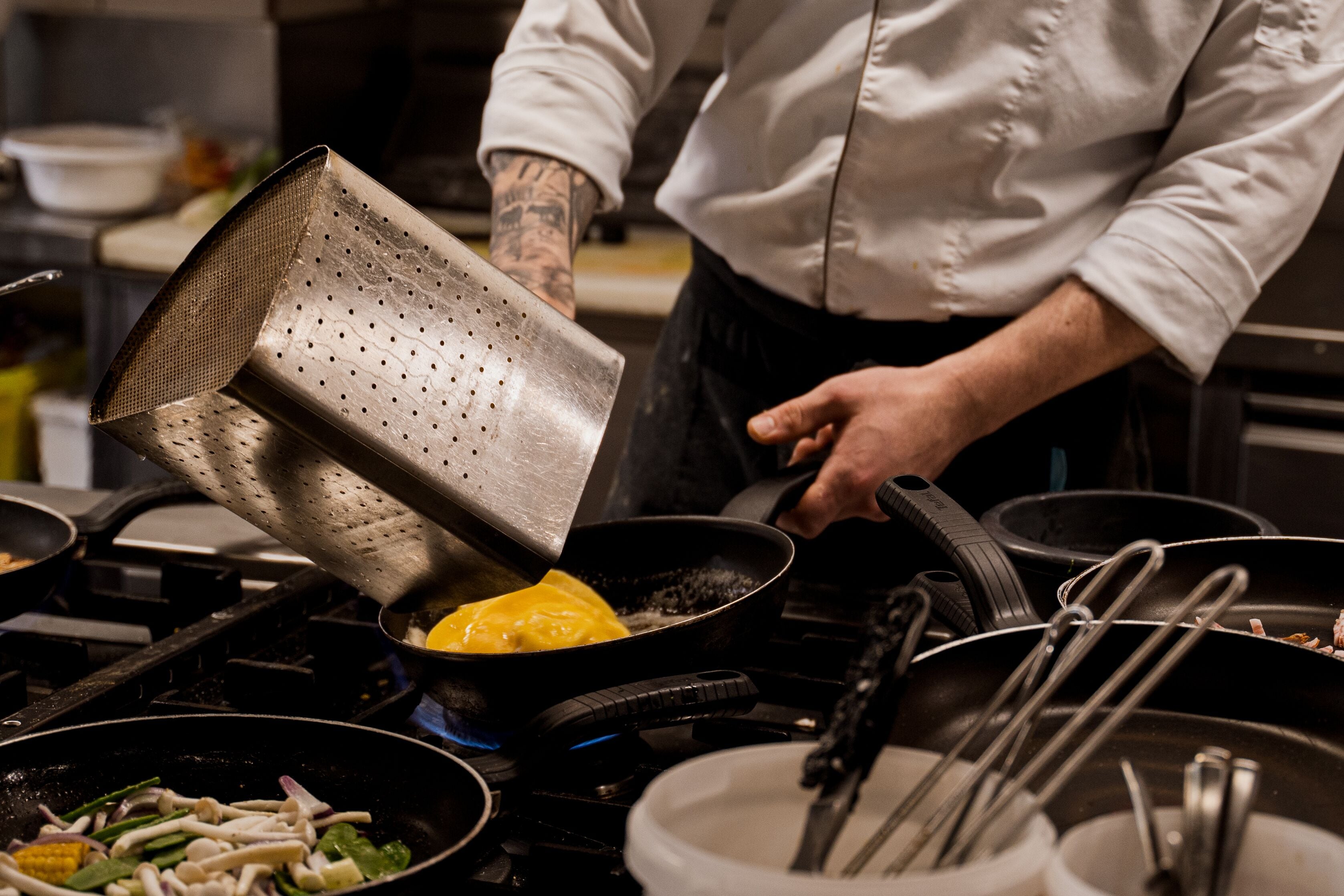 A chef cooking in a kitchen with various utensils and cookware.