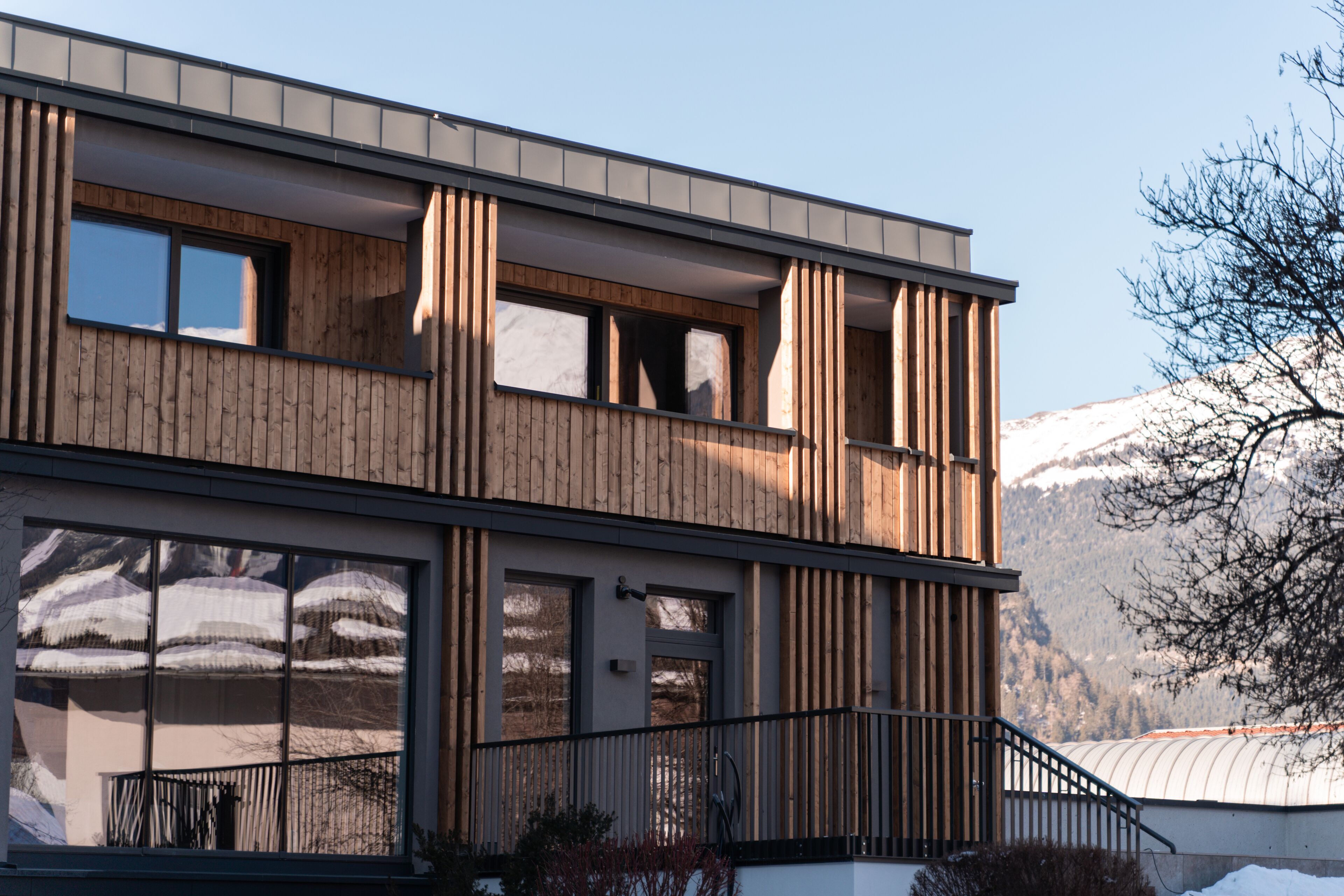 A modern building with a wooden facade, large windows, and a balcony.