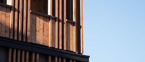 A modern building with vertical wooden slats and a balcony railing.