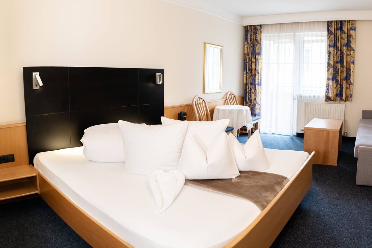 A hotel room with a bed, a sofa, a TV, and a desk.