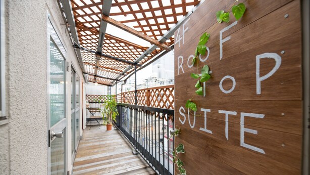 A wooden sign with the text "4 ROOF 4 SUITE" and a wooden balcony with a metal railing. - Dotombori Base - Hostel (Osaka)