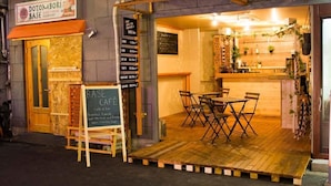 A cozy cafe with a wooden deck, tables, and chairs. - Dotombori Base - Hostel (Osaka)