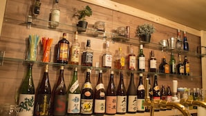 A bar area with shelves of various liquor bottles and glasses. - Dotombori Base - Hostel (Osaka)