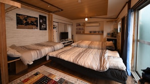A compact room with two beds, a television, and a bookshelf. - Dotombori Base - Hostel (Osaka)