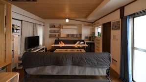 A room with a bed, a TV, a bookshelf, and a window. - Dotombori Base - Hostel (Osaka)