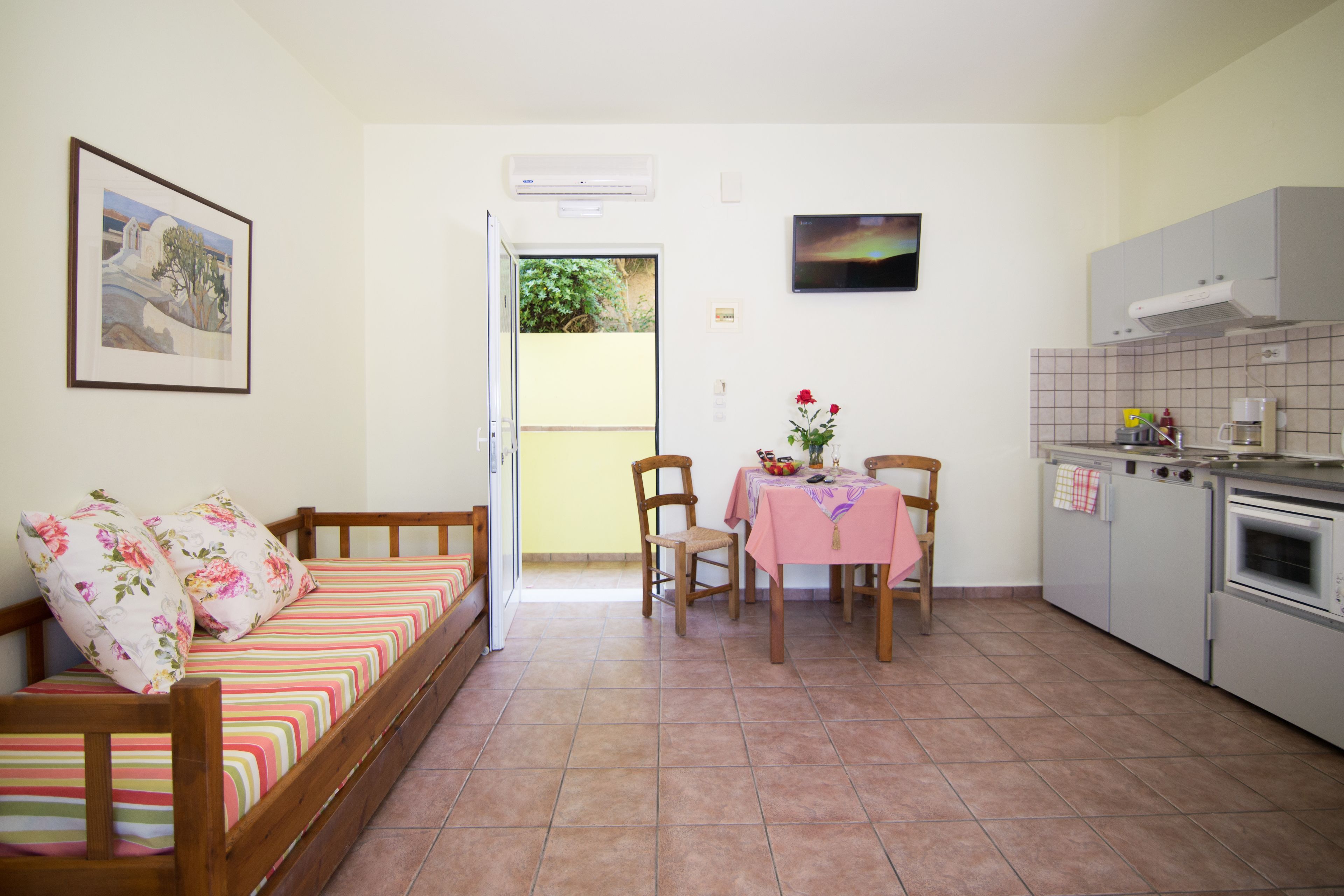 Un espacio habitable compacto con sofá, mesa de comedor, sillas y kitchenette.