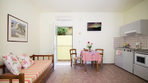 A compact living space with a sofa, dining table, chairs, and a kitchenette. - Kalithea Apartments (Apokoronas)