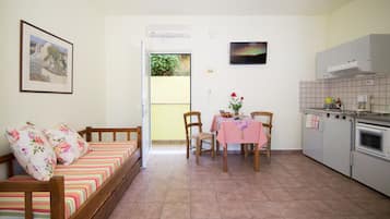 Un espacio habitable compacto con sofá, mesa de comedor, sillas y kitchenette.