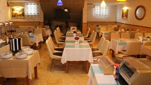 A restaurant with multiple dining tables, chairs, and a buffet area with food containers. - Selimiye  (Edirne)