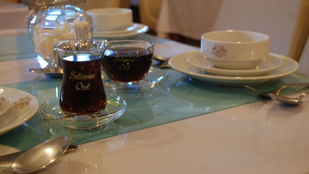 A dining table with a clear glass pitcher, two glasses of tea, and a white teapot.