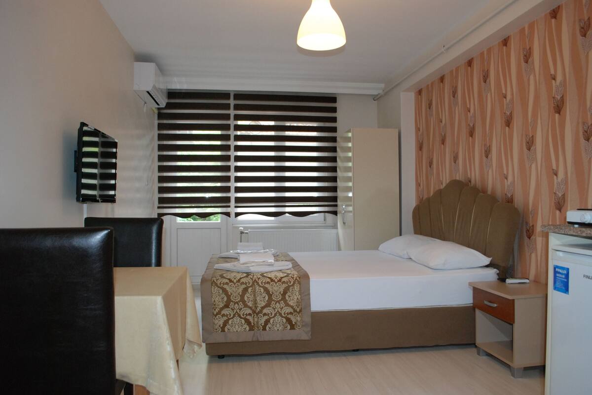 Una camera d'albergo con un letto, un comodino e una sedia.