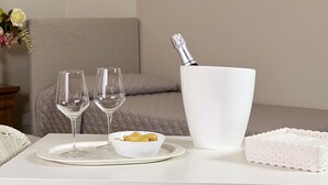 A white table with two wine glasses, a bowl of snacks, a bottle of champagne, and a decorative item. - La Maison One B&B (Carovigno)