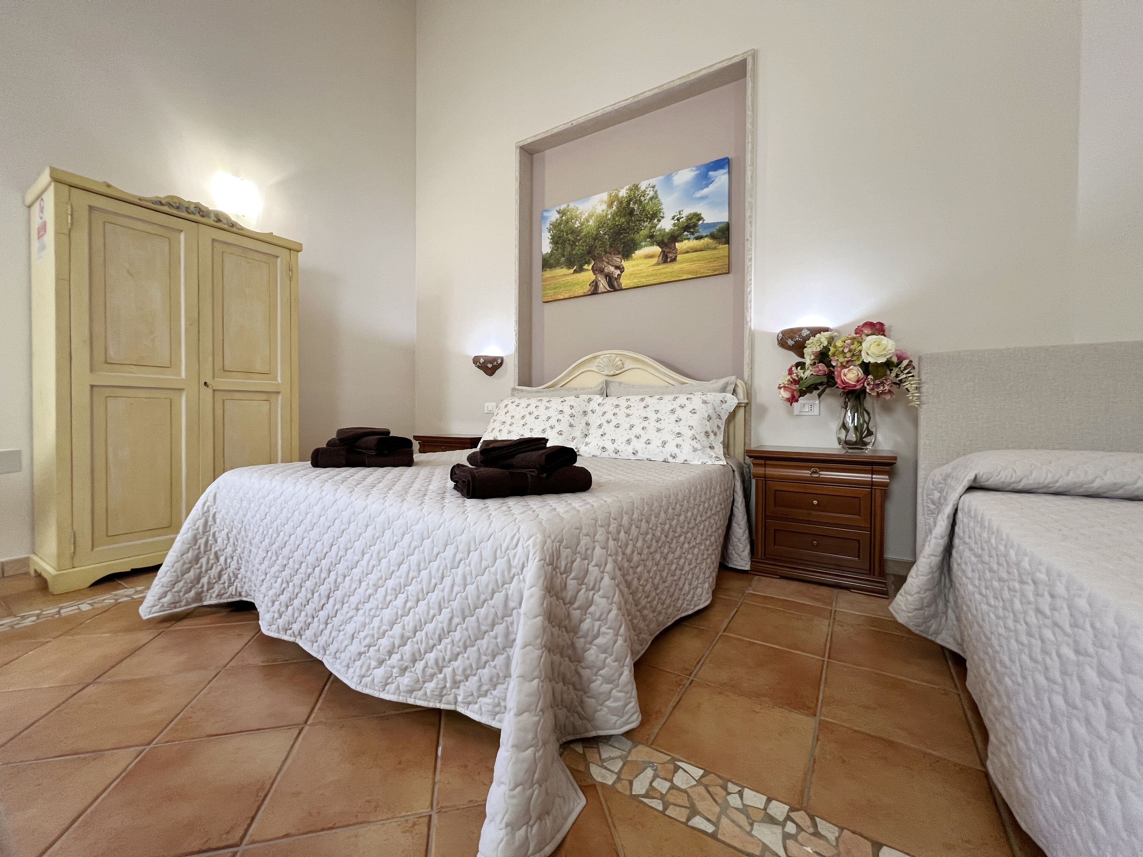 Un dormitorio con cama, mesita de noche, cómoda y un cuadro en la pared.