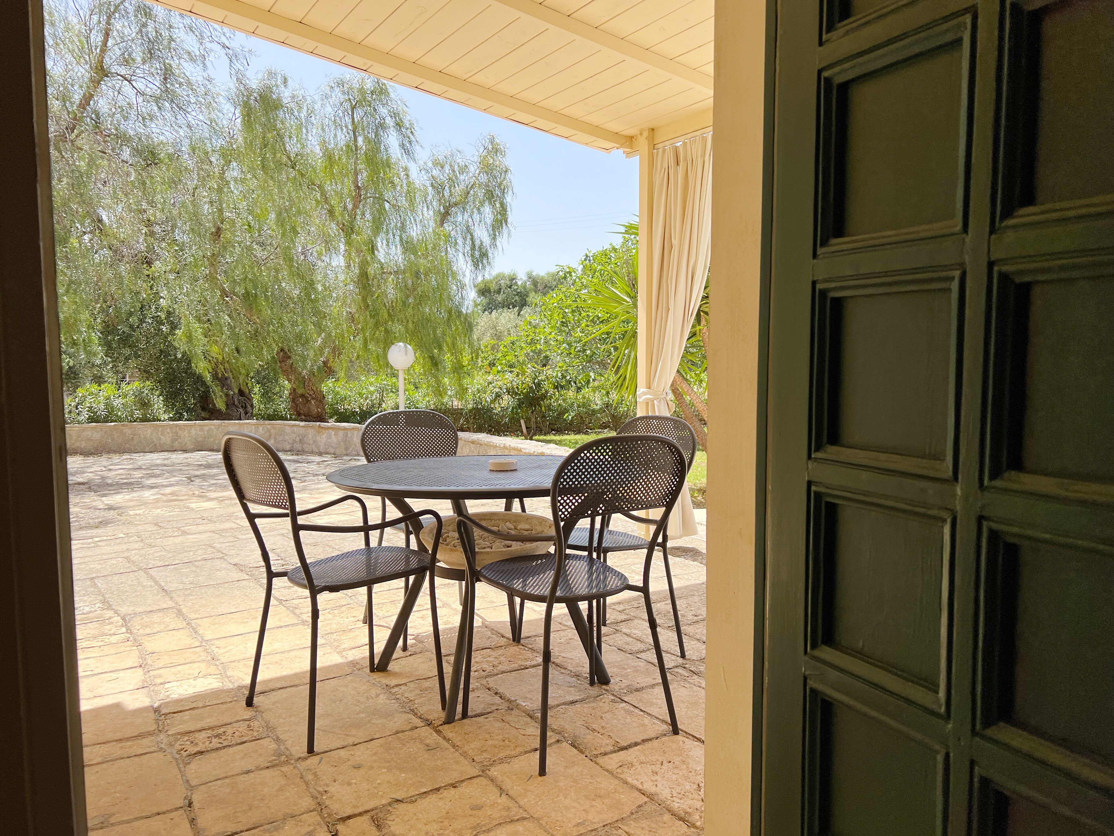 Una terrazza all'aperto con tavolo e sedie, una lampada e vista su alberi e vegetazione.