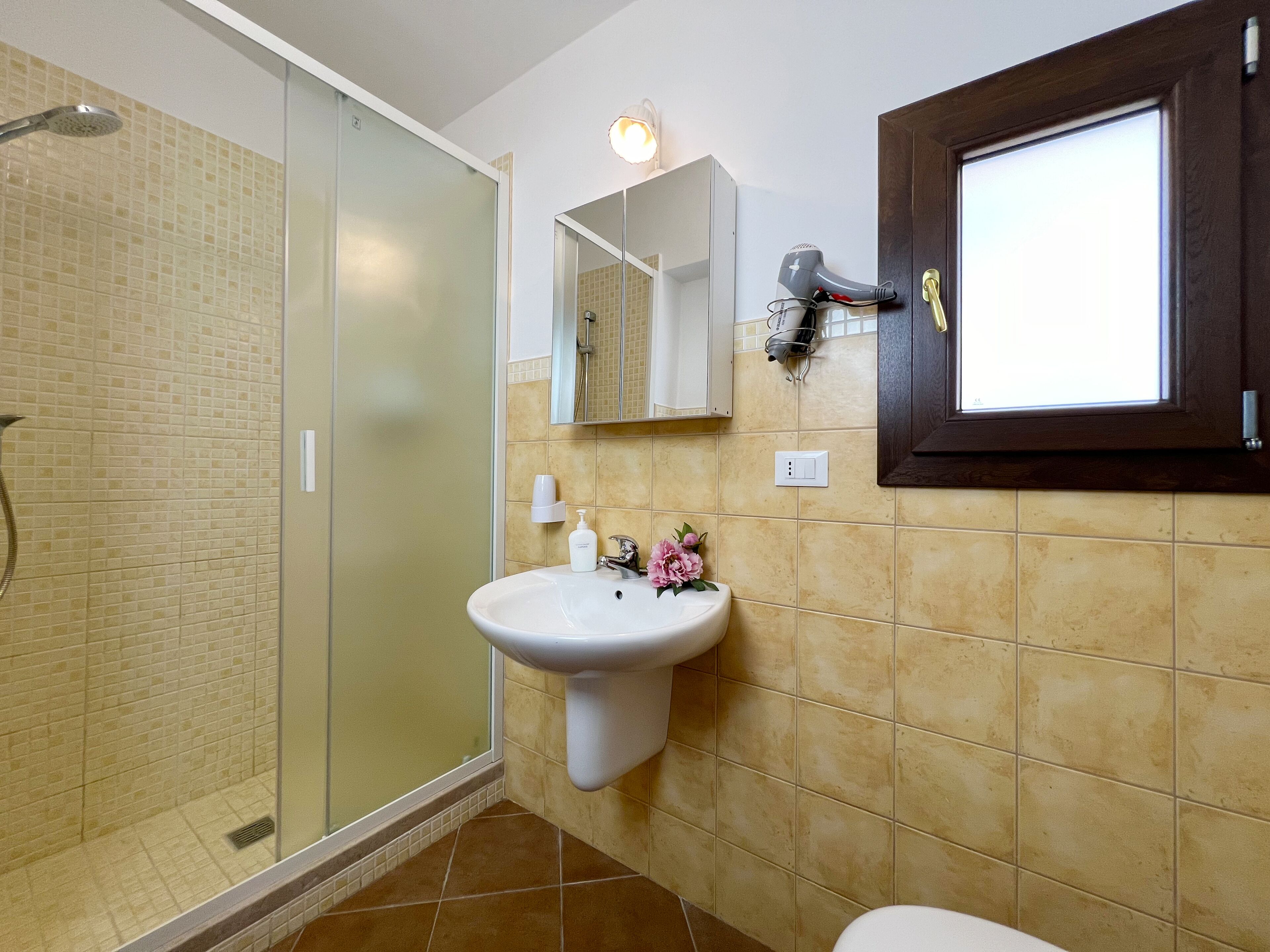 Un baño con cabina de ducha de vidrio, un lavabo con espejo y un inodoro.