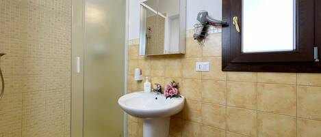 Un baño con cabina de ducha de vidrio, un lavabo con espejo y un inodoro.