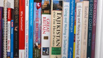 Una estantería con varios libros de viajes.