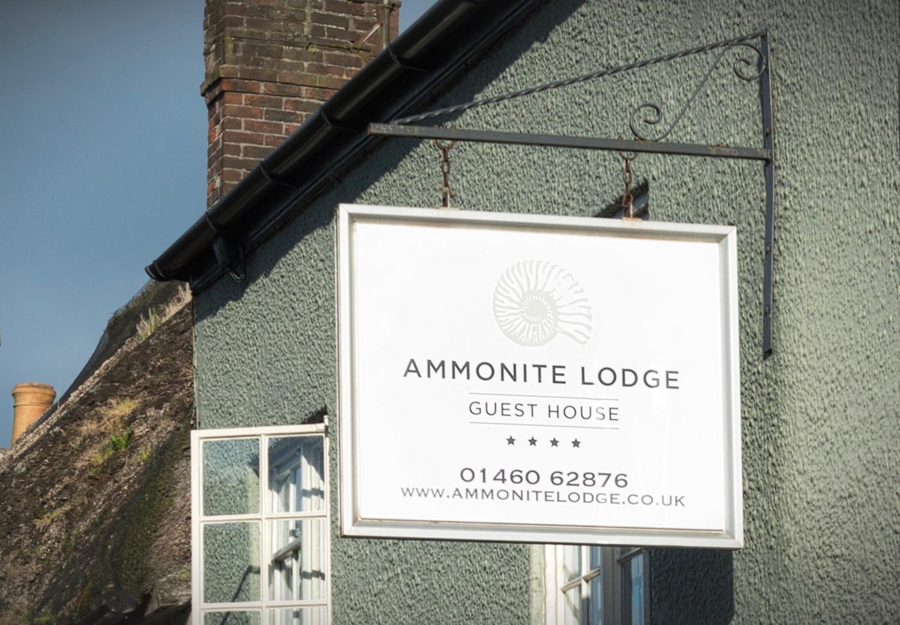 Señalización para Ammonite Lodge, una casa de huéspedes, con información de contacto y una dirección web.