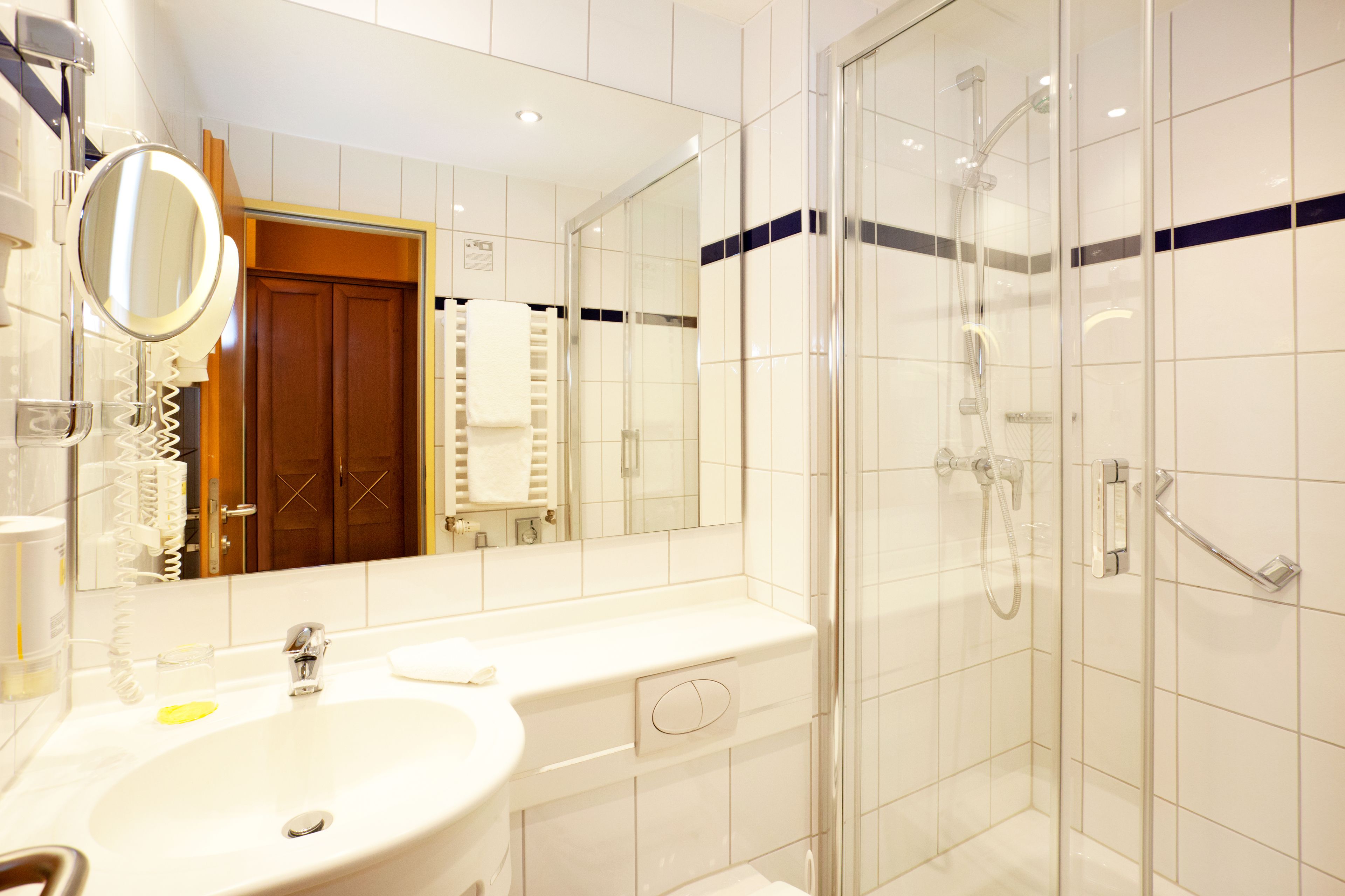 A modern bathroom with a sink, mirror, and glass-enclosed shower.