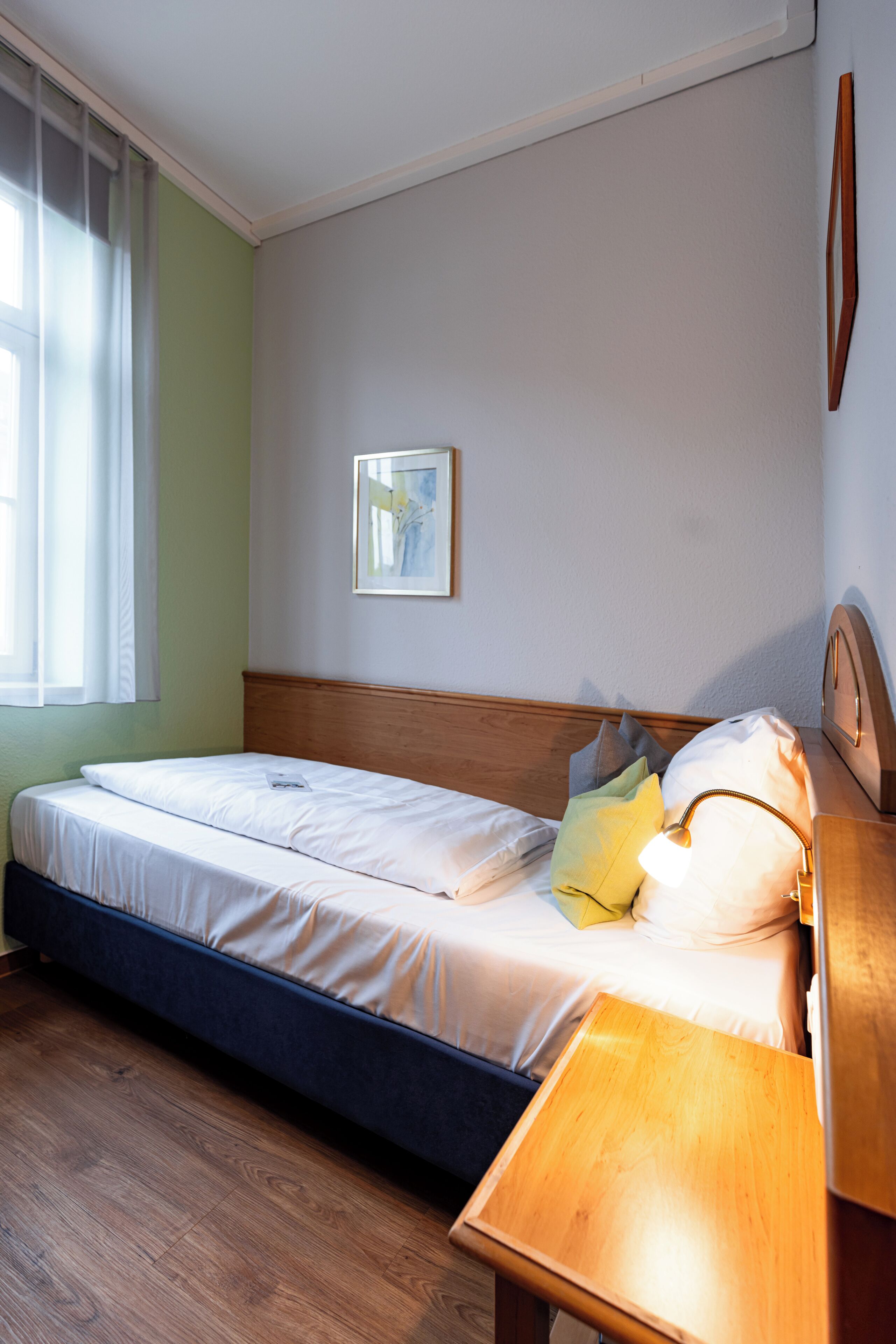 A double bed with a wooden headboard, a bedside table, and a wall-mounted clock.