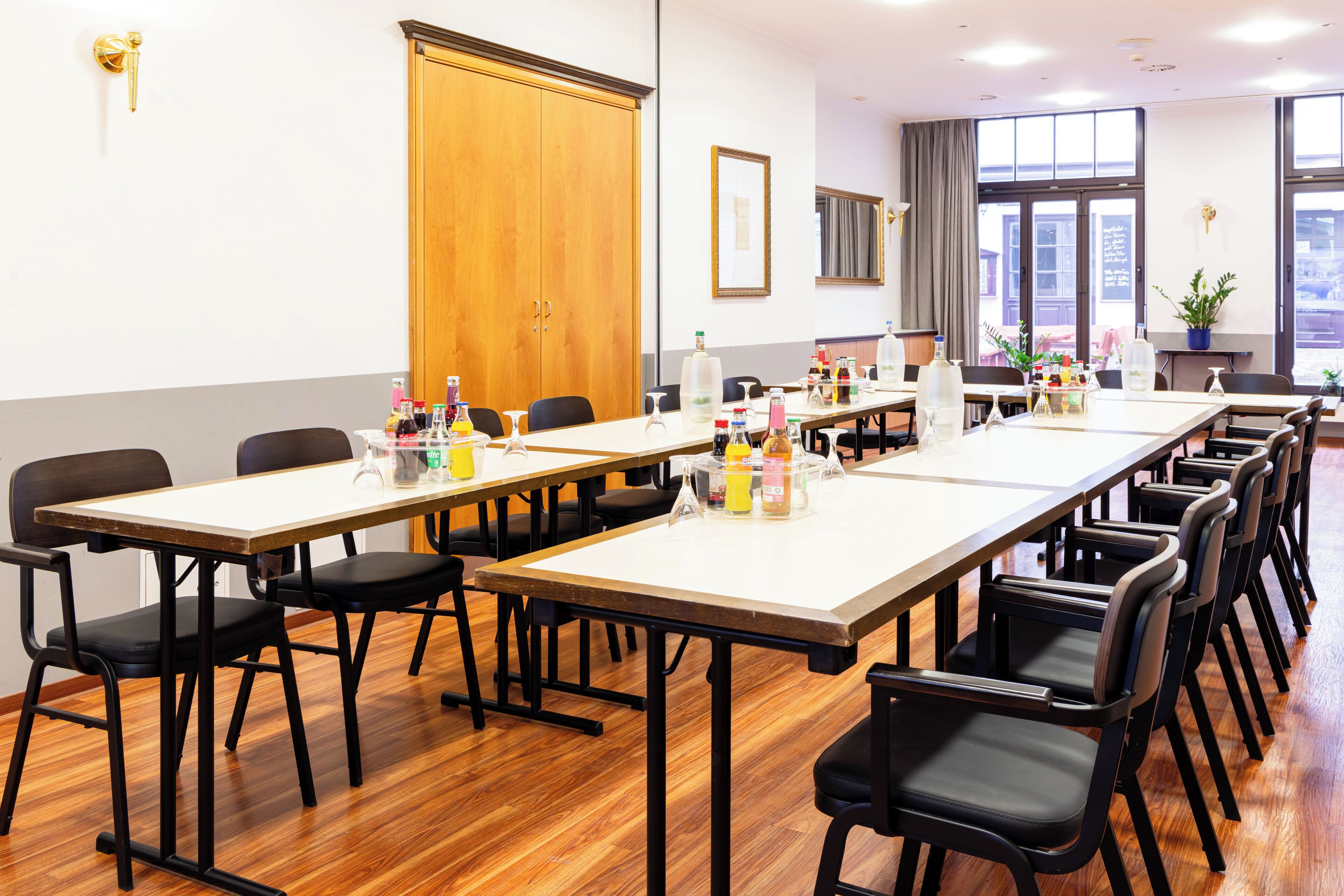A conference room with long tables, black chairs, and various items on the tables.