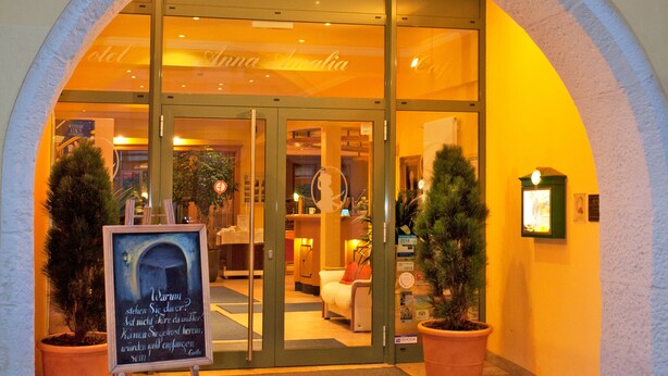 La entrada del Hotel Anna Amalia, con un arco visible, un cartel y plantas en macetas.