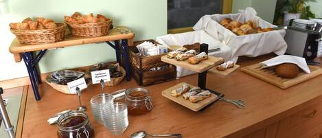Un buffet de petit-déjeuner proposant un assortiment de viennoiseries, de pains et de condiments.