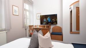 Habitación de hotel con cama, dos almohadas, escritorio, silla, televisor y espejo.