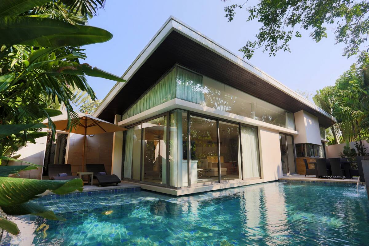 A modern house with a swimming pool, large glass windows, and outdoor furniture.